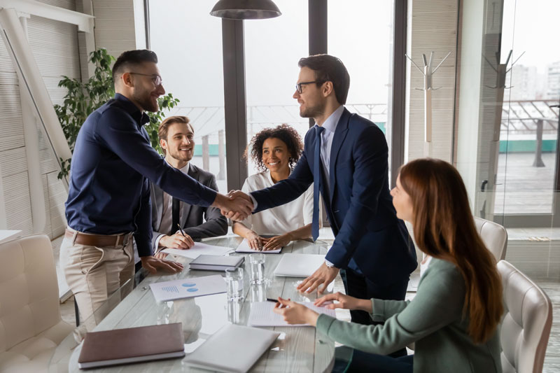 Grupo de empresarios en una sala de juntas cerrando un negocio