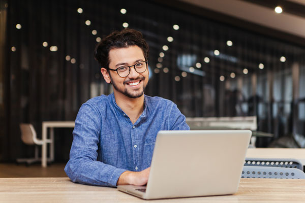 Hombre sonriendo y utilizando su computador portatil