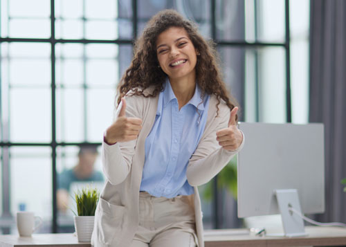 Mujer sonriendo con los pulgares arriba en señal de optimismo